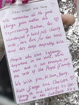 Prince William takes flowers and notes from the public which he placed among other tributes. Picture: AP