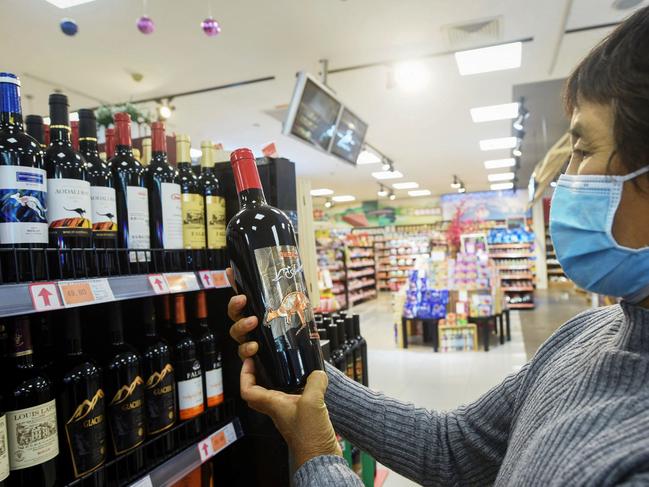 A woman looks at a bottle of Australian wine at a supermarket in Hangzhou, in eastern China's Zhejiang province on November 27, 2020. (Photo by STR / AFP) / China OUT