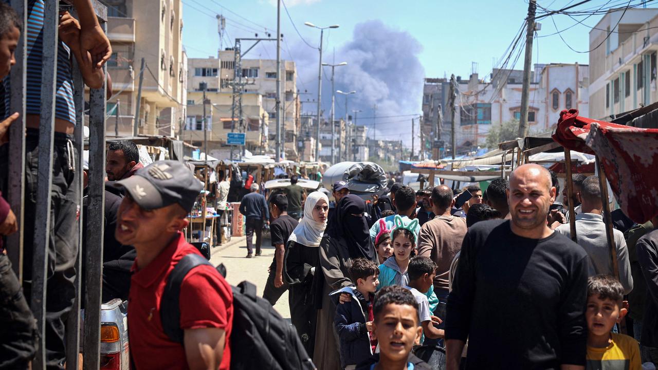 Palestinians crowd a street as smoke billows nearby from Israeli strikes in Rafah in the southern Gaza Strip on May 7, 2024, amid the ongoing conflict between Israel and the Palestinian militant group Hamas. (Photo by AFP)