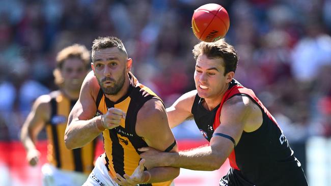 MELBOURNE, AUSTRALIA – MARCH 16: Jack Gunston of the Hawks handballs whilst being tackled by Zach Reid of the Bombers during the round one AFL match between Essendon Bombers and Hawthorn Hawks at Melbourne Cricket Ground, on March 16, 2024, in Melbourne, Australia. (Photo by Quinn Rooney/Getty Images)