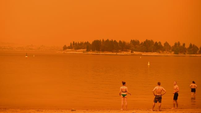 Residents take a dip to cool down at Lake Jindabyne, NSW, under a red sky due to smoke from bushfires. The fires devastating NSW and Victoria are also affecting the NT economy with a flow-on impact on Territory tourism. Picture: Saeed Khan/AFP