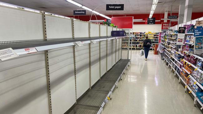 A shopper walks past empty toilet paper shelves in a Melbourne supermarket on Friday. Picture: AFP