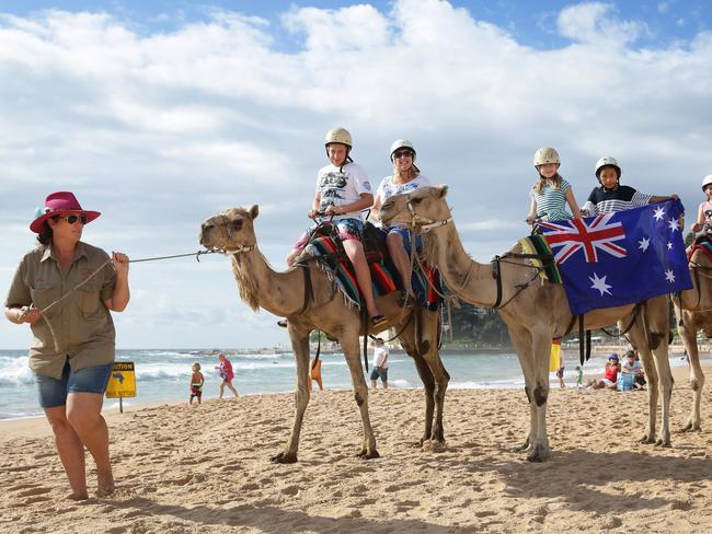 Annabelle Robinson, 9, of Forestville and Wangmo Choephel, 9, of Dee Why unfurl the Aussie flag from atop the camel. Picture: Martin Lange