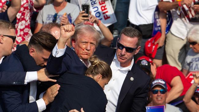 Republican candidate Donald Trump is seen with blood on his face surrounded by secret service agents as he is taken off the stage at a campaign event at Butler Farm Show Inc.