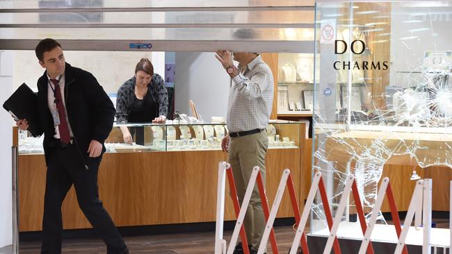 A detective leaves the jewellery store. The smashed window can be clearly seen. Picture: Lawrence Pinder