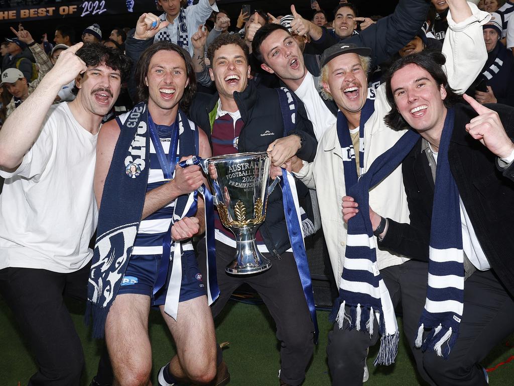 Jack Henry of the Cats (2L) holds the premiership cup as he celebrates with friends after winning the 2022 AFL Grand Final. Picture: Daniel Pockett