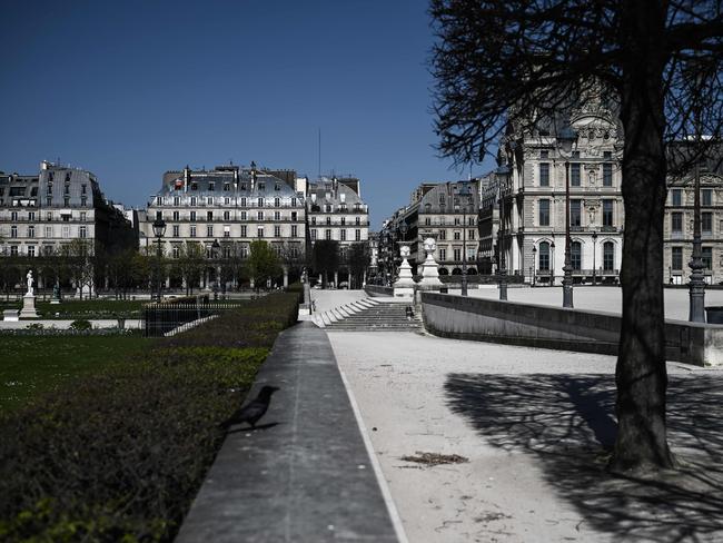 A woman (C) sits on stairs in front of the deserted Louvre palace in Paris. Picture: AFP