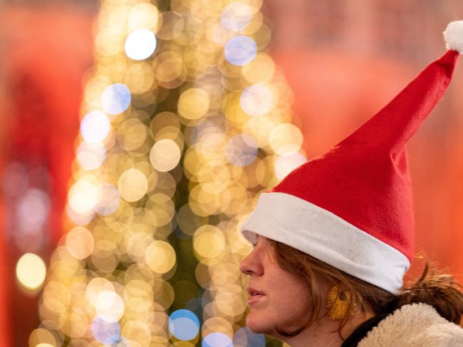 A woman wears a Christmas hat in front of the Christmas lights at the city center of Vienna, Austria on November 15, 2024. While just two years ago Vienna reduced its Christmas lightening to save costs, this year the Austrian capital has decided to spend more to ensure the lights shine ever as bright on its iconic markets. Chandeliers, glittery stars, red globes and other designs are lighting 31 Vienna streets from November 15. This year the city and the economic chamber cover 75 percent instead of 50 percent of the costs, or some 700,000 euros for the lighting alone, as the economy struggles. (Photo by JOE KLAMAR / AFP)