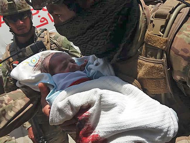 An Afghan security personnel carries a newborn baby from a hospital, at the site of an attack in Kabul on May 12, 2020. - Gunmen stormed a hospital on May 12 in an ongoing attack in the Afghan capital Kabul, a government official and a fleeing doctor said. (Photo by STR / AFP)