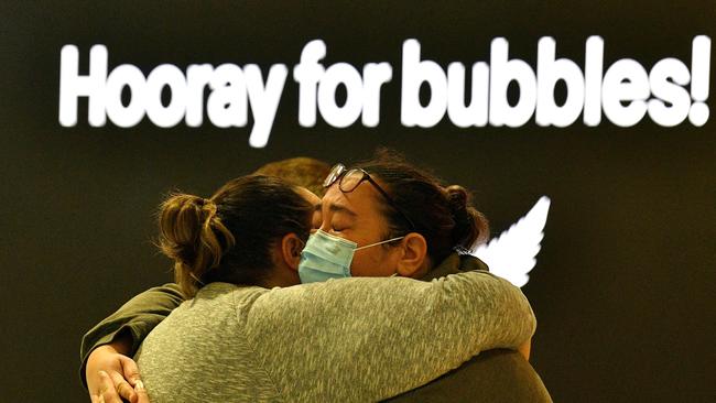 A woman hugs a family member before his departure for New Zealand at Sydney International Airport.