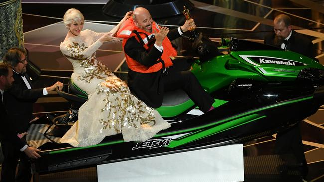 Helen Mirren and Oscar-winning costume designer Mark Bridges sitting on the jet ski that was the prize for shortest acceptance speech. Picture: Getty