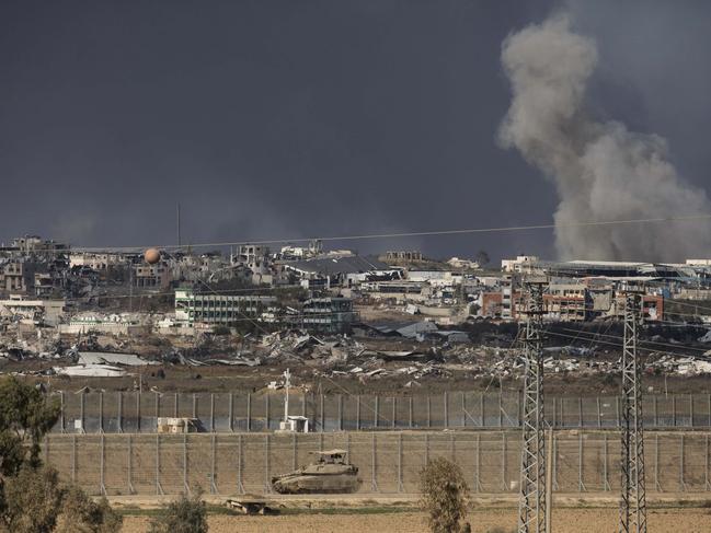 An Israeli tank moves along the border with Gaza as smoke rises in the distance. Picture: Getty Images