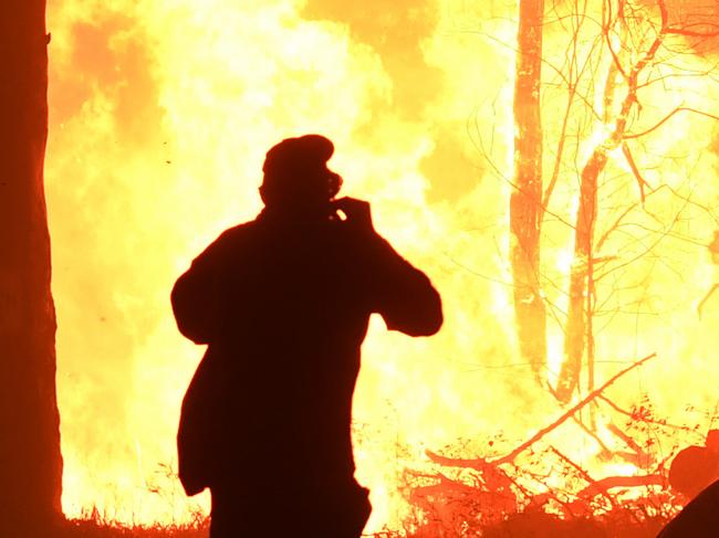 RFS volunteers and NSW Fire and Rescue officers fight a bushfire encroaching on properties near Termeil on the Princes Highway between Batemanâ€™s Bay and Ulladulla south of Sydney,Tuesday, December, 3, 2019. (AAP Image/Dean Lewins) NO ARCHIVING