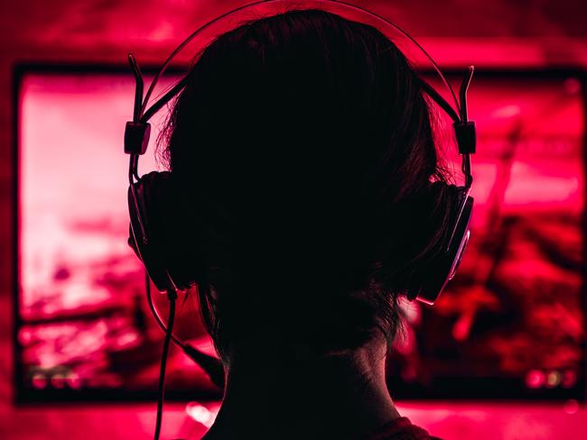 Woman wearing headphones playing video games late at night. Video games, gaming, screen time, kids and technology, headphones, generic