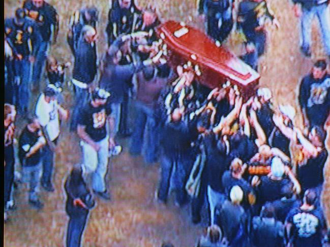 Mourners pass the coffin above their heads.