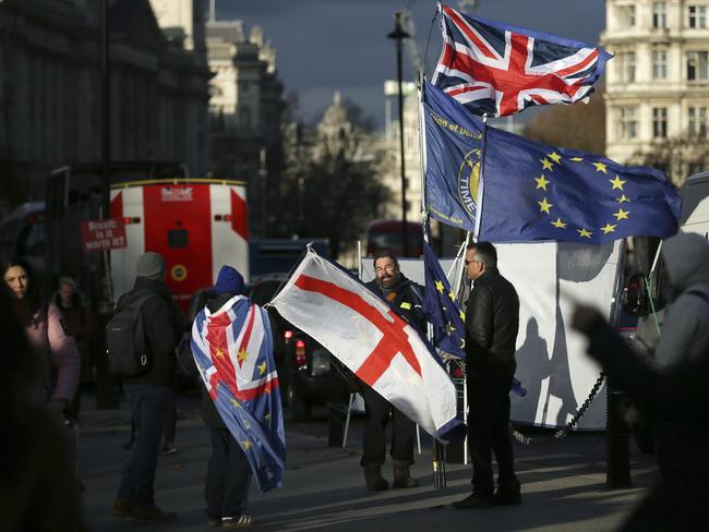 Anti-Brexit protesters wave flags outside the Houses of Parliament, in London, Wednesday December 12, 2018. British Conservative lawmakers forced a no-confidence vote in Prime Minister Theresa May for Wednesday, throwing U.K. politics deeper into crisis and Brexit further into doubt. (AP Photo/Tim Ireland)