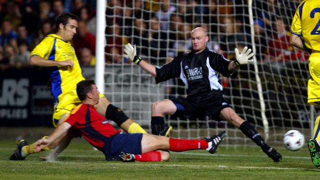 Carl Veart slides home Adelaide United’s first goal in its maiden game against Brisbane Strikers at a packed Hindmarsh.