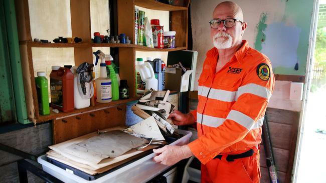 Larry Nolan from Manning Point sifts through his water damaged old Army service mementos. Pic Nathan Edwards