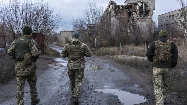 Ukrainian soldiers walk past destroyed buildings on the front line. Picture: Getty Images.