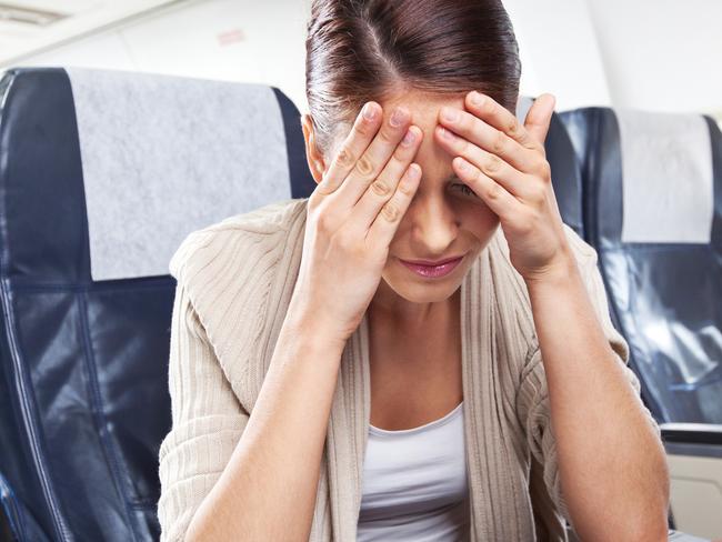 A young woman sitting on an airplane and suffering from headache.