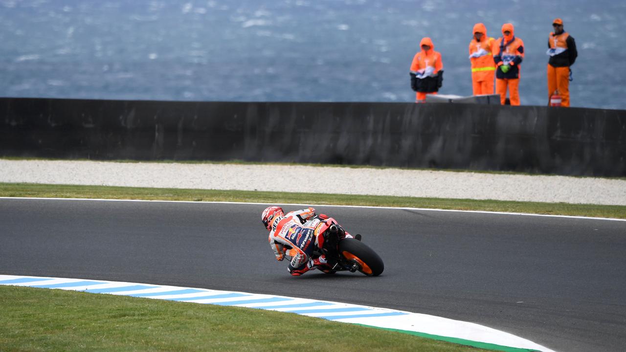 Marc Marquez speeds through a corner as marshals stand through the wind and rain. Picture: William West