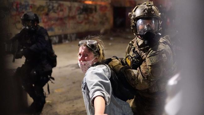 Federal officers arrest a protester after she crossed a fence line set up around the Mark O. Hatfield US Courthouse. Picture: AFP