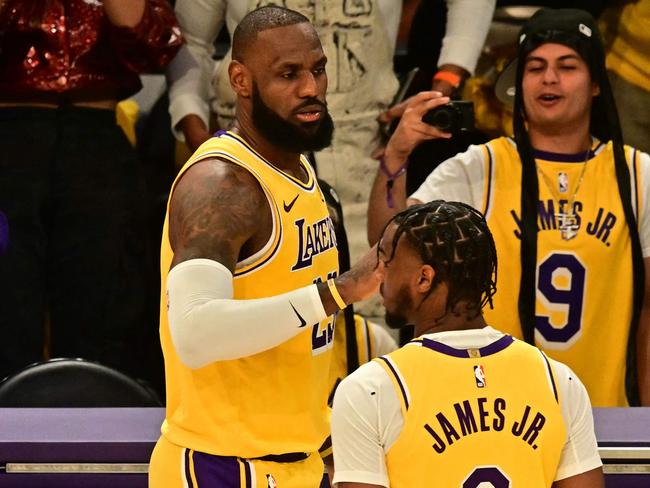 Los Angeles Lakers' US small forward #23 LeBron James (L) and Los Angeles Lakers' US guard #09 Bronny James are seen on court during the NBA game season opener between the Los Angeles Lakers and the Minnesota Timberwolves at Crypto Arena in Los Angeles on October 22, 2024. LeBron and Bronny are the first father and son to play together in any NBA game. (Photo by Frederic J. Brown / AFP)