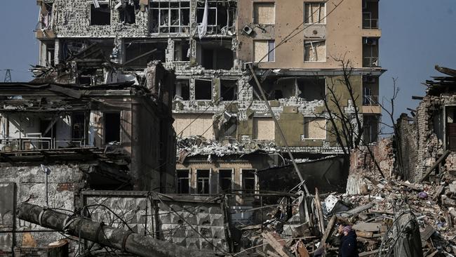 A couple walk in front of houses destroyed by shelling in Kharkiv. Picture: AFP