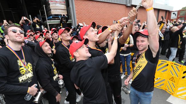 Glenelg coach Mark Stone helps players unveil the Tigers’ colours on the West End Brewery chimney on Tuesday. Picture: TAIT SCHMAAL