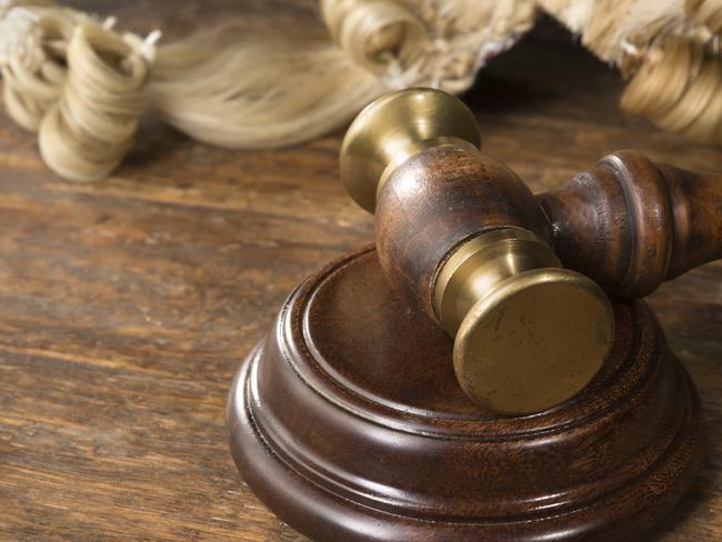 Wooden block, judge's wig and gavel on a wooden desk