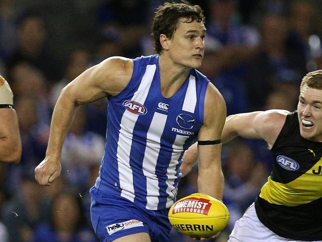 Scott Thompson of the Kangaroos handpasses under pressure from Jacob Townsend of the Tigers during the Round 8 AFL match between the North Melbourne Kangaroos and the Richmond Tigers at Etihad Stadium in Melbourne, Sunday, May 13, 2018. (AAP Image/Hamish Blair) NO ARCHIVING, EDITORIAL USE ONLY