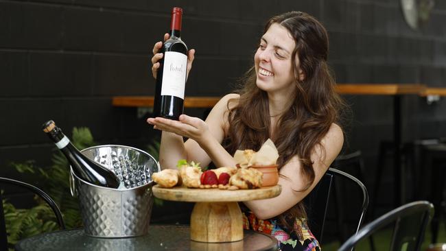 Mucho Love cafe at Edge Hill has begun serving South American wines, cheese and tapas plates three nights a week. Mucho Love co owner Micaela Lukac serves up some Argentinian wine and empanadas in the cafe's outdoor courtyard. Picture: Brendan Radke