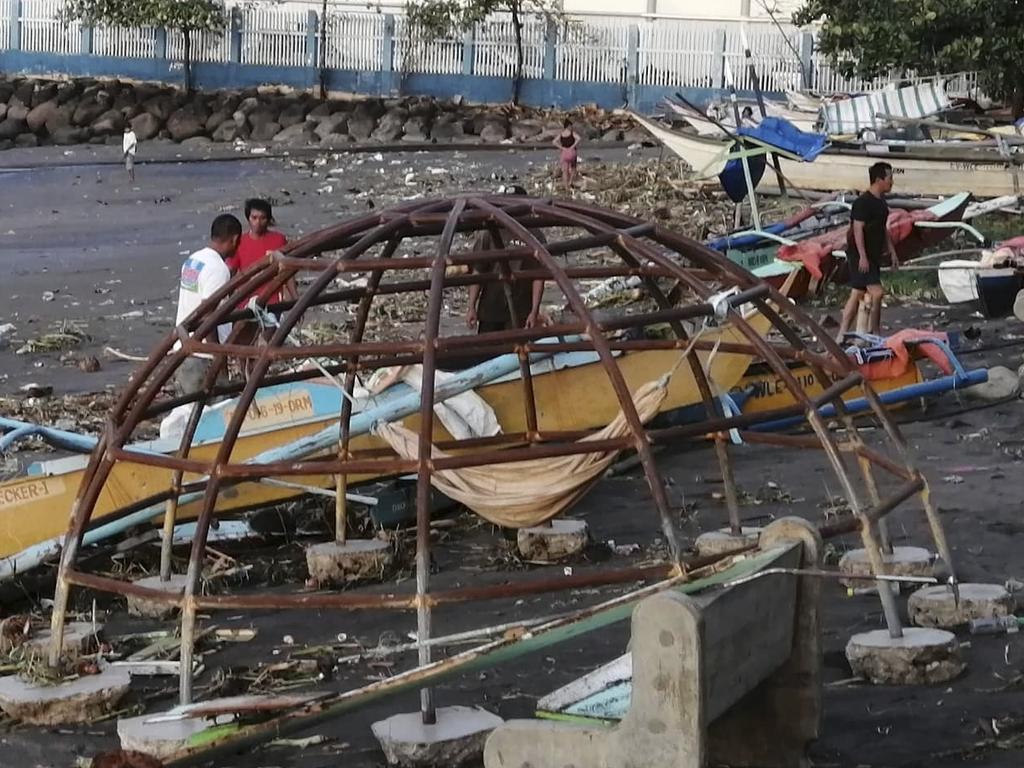 Residents walks beside an outrigger and playground equipment that were damaged by Typhoon Phanfone along a coastline in Ormoc city, central Philippines. Picture: AFP