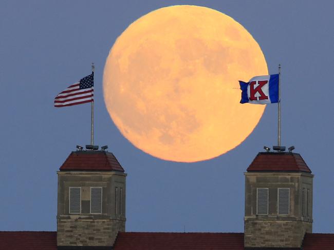 The moon rises beyond flags atop Fraser Hall on the University of Kansas campus in Lawrence, Kan., Sunday, Nov. 13, 2016. Monday morning’s supermoon was to be the closest a full moon has been to Earth since Jan. 26, 1948. (AP Photo/Orlin Wagner)