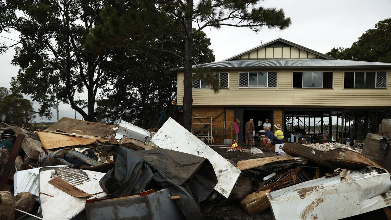 Geoff and Jennie Youll enjoy a drink around a campfire with family and friends after cleaning out their property in Woodburn that was hit hard when the Richmond River flooded the town. Picture: Jonathan Ng