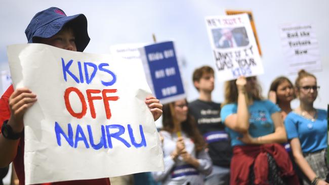 Protesters hold up signs during a rally outside parliament demanding the resettlement of chlidren on Nauru. Picture: AAP.