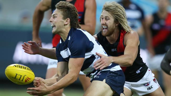 Tom Atkins handballs clear as he is tackled by Essendon captain Dyson Heppell. Picture: Michael Klein