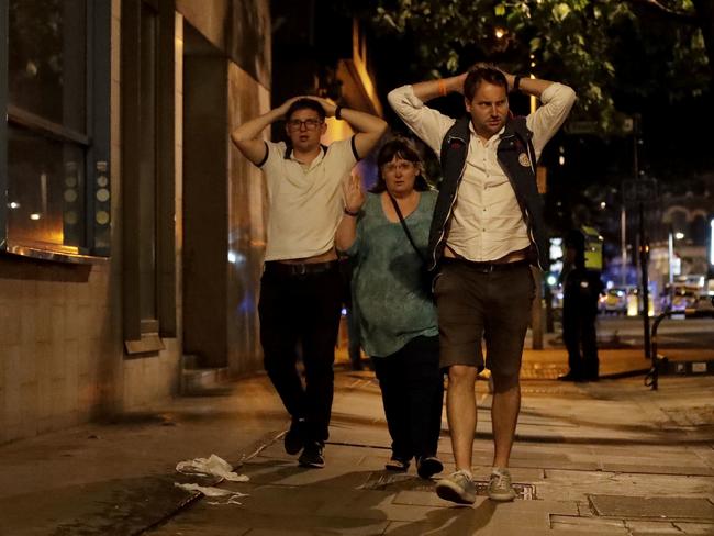 People with their hands on their heads about 10 minutes after midnight as they leave from inside a police cordon after an attack in London. Picture: AP