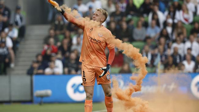 Tom Glover picks up a flare to remove it before angry fans rushed on to the pitch and surrounded him. Picture: Darrian Traynor/Getty Images