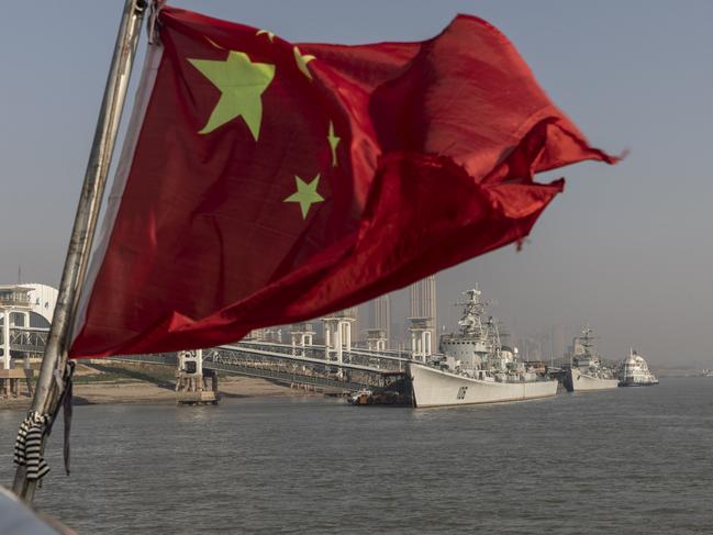 A Chinese national flag flies before Chinese frigate ships. Picture: Qilai Shen