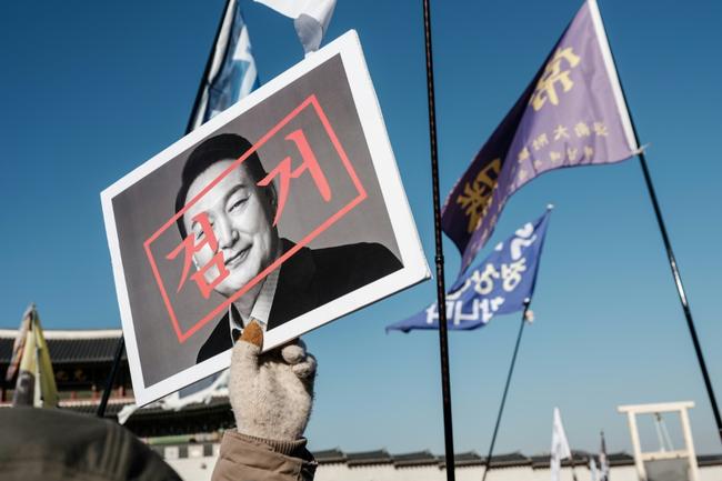 A protester walks with a portrait of impeached South Korean President Yoon Suk Yeol before a rally in Seoul