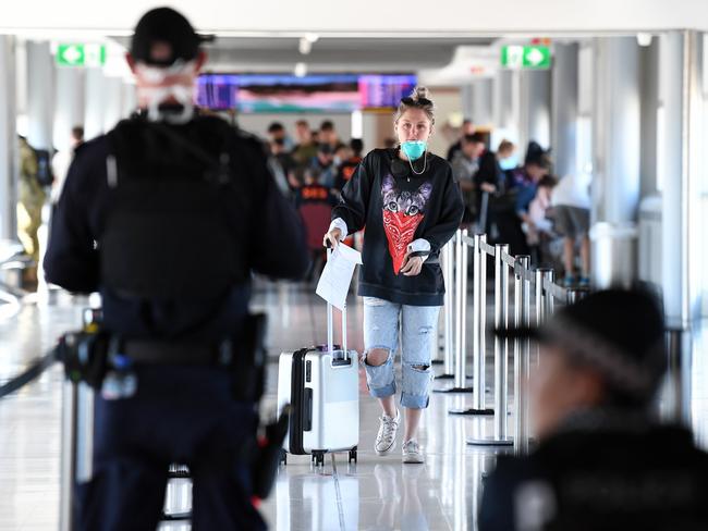 Police screen incoming passengers at the domestic airport in Brisbane, Friday, April 3, 2020. From today, only residents or those with a permit are allowed to enter Queensland as part of the state government's battle against COVID-19. (AAP Image/Dan Peled) NO ARCHIVING