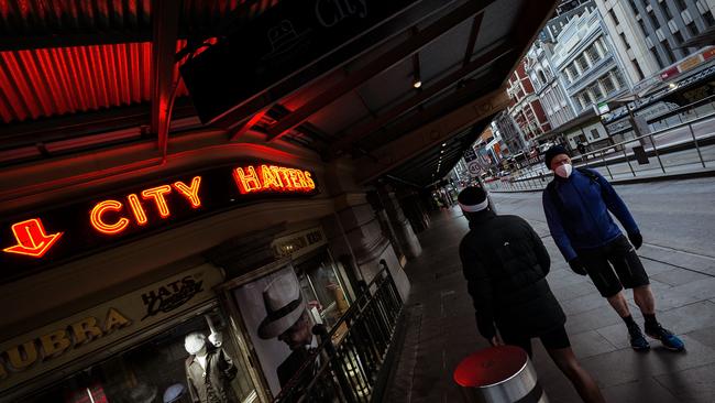 People wearing masks walk past closed shops in Melbourne’s CBD this week. Picture: Getty