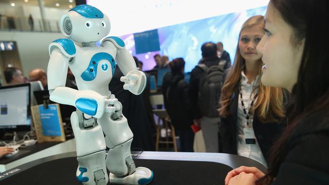 HANOVER, GERMANY - MARCH 14: A stand hostess talks to a NAO Watson robot at the IBM stand at the 2016 CeBIT digital technology trade fair on the fair's opening day on March 14, 2016 in Hanover, Germany. The 2016 CeBIT will run from March 14-18. (Photo by Sean Gallup/Getty Images)