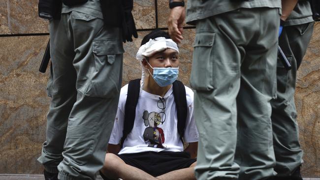 Riot police guard a protester as a second reading of a controversial national anthem law took place in Central district, Hong Kong on Wednesday. Picture: AP Photo/Kin Cheung.