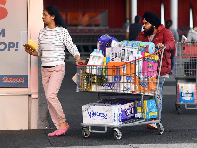 People leave a Costco outlet with a trolley full of toilet paper and cleaning products as fears of a second wave of COVID-19 have sparked a rush on some supermarket items in Melbourne on June 24, 2020. - Major supermarkets in the state of Victoria have reimposed buying limits on toilet paper and other essentials after a renewed escalation in demand sparked fears of a return to scenes of panic-buying seen early in the pandemic. (Photo by William WEST / AFP)