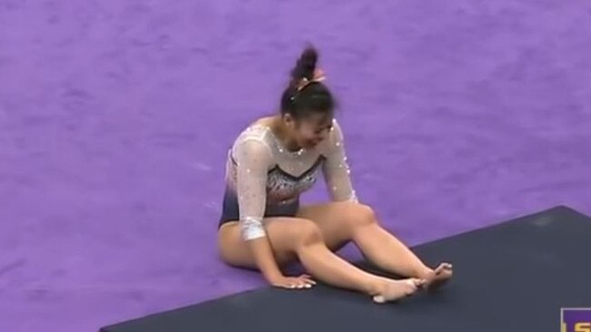 The gymnast writhes in pain.