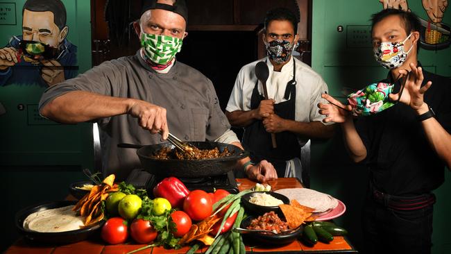 Hispanic Mechanic co-owner / chef Greggory Hill with line chef Mani Gill and restaurant manager Vinh Dang wearing the masks Greg commissioned his friend to make. Picture: Tricia Watkinson