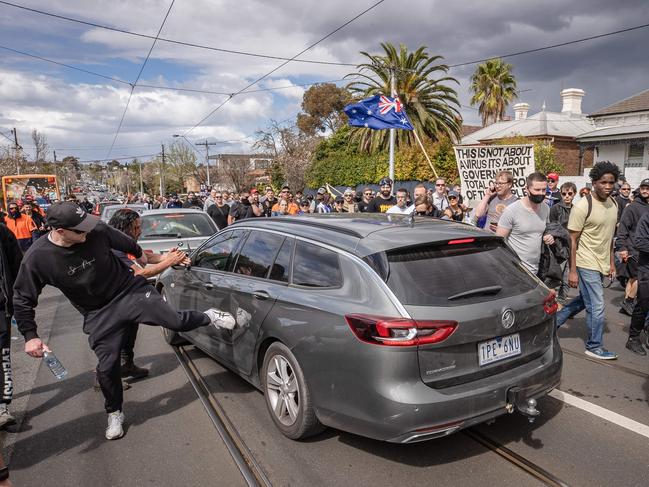 An anti-lockdown protester kicks an unmarked police vehicle in Richmond. Picture: Jason Edwards