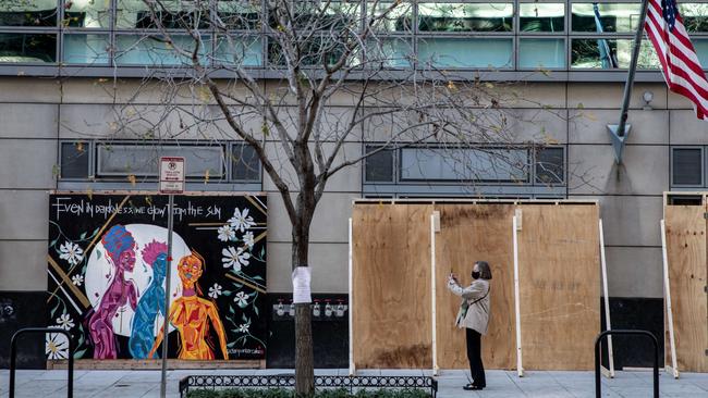 A woman takes a photograph of a shop that is boarded up as a precaution to unrest related to the presidential election. Picture: AFP